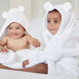 Two babies in white bear hooded towels on a neutral background