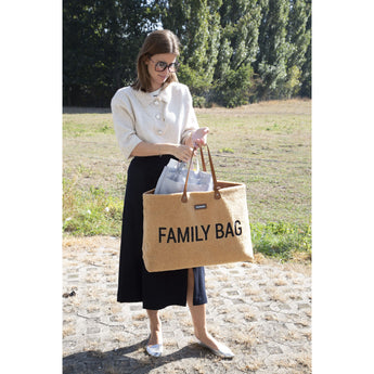 Woman holding a large, fluffy brown "FAMILY BAG" tote with leather handles, containing a smaller grey bag.