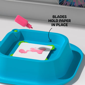 Blue Discovery 3D Neon Spin Art Station with pink paint dripping onto a white paper held by green blades.
