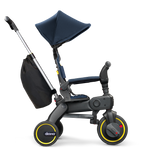 Doona Liki Trike S3 in navy blue and black with yellow accents, a canopy, and storage bag.