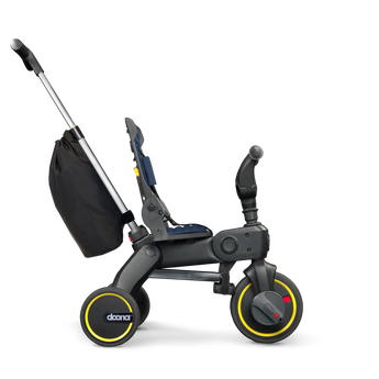 Doona Liki Trike S3 kids tricycle in black with yellow accents, a navy seat, and a rear storage bag.