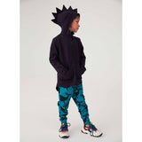 Boy wearing a navy Kuku Kid Dino Hoodie Cardigan Jacket with spiked hood and blue whale-print leggings.