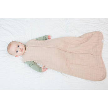 Baby in a light pink Lulujo 100% cotton muslin sleep sack with a full-length zipper.