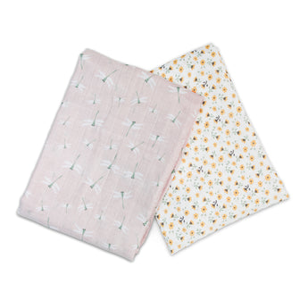 Two folded Lulujo cotton muslin swaddles: one pink with dragonflies, one white with yellow floral print.