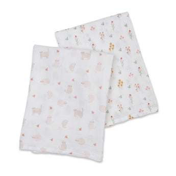Two Lulujo cotton muslin swaddles: one with pink cats, one with colorful wildflowers.