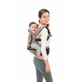 Woman carrying baby in a gray MiaMily Hipster ergonomic baby carrier with hip seat.