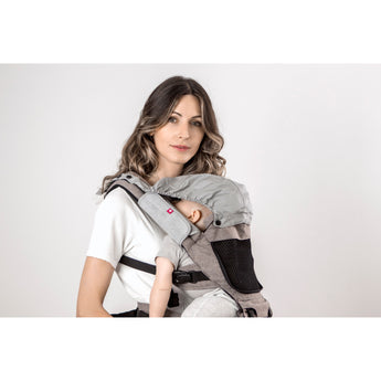 Woman wearing a gray and beige MiaMily Hipster baby carrier with a sleeping infant.