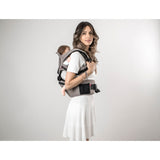 Woman wearing a gray MiaMily Hipster ergonomic baby carrier with a baby on her back.