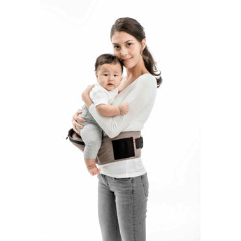 Smiling mom holds baby in a brown MiaMily Hipster ergonomic baby carrier with hip seat.