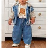 Baby wearing a personalized white wooden camera toy with a strap, denim outfit, and neutral top.