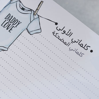 Close-up of a baby milestone album page with a "DADDY LOVE" onesie illustration and Arabic text.
