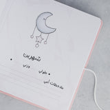 Open pink baby milestone album page with a moon and stars illustration and Arabic text.