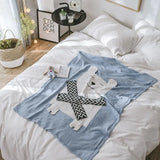 Light blue personalized animal theme blanket with a white polar bear design and black and white zigzag scarf, on a white bed.