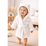 Smiling baby in a white organic cotton hooded bathrobe with bear ears and "Jack" embroidered in blue.