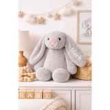 Soft gray personalized bunny plush toy with "Mark" embroidered on its ear, sitting on a white dresser.