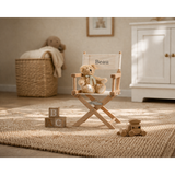 Personalized children's director chair with "Beau" on white canvas, French oak wood frame, teddy bear, and wooden toys.