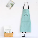 Light blue kids bear apron with black straps and a front pocket, hanging on a white wall.