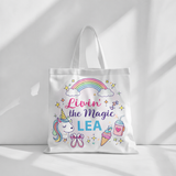 White cotton tote bag with "Livin' the Magic LEA" text, unicorn, rainbow, ballet shoes, and ice cream design.