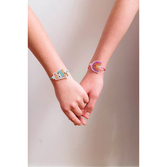 Two children's hands holding, each wearing a colorful Ooly Shrink Its! DIY shrink art bracelet.