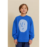 Kid in blue organic cotton oversized sweatshirt with light blue potato face print.