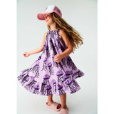 Child wearing a purple dress with jellyfish pattern and pink cap on a white background