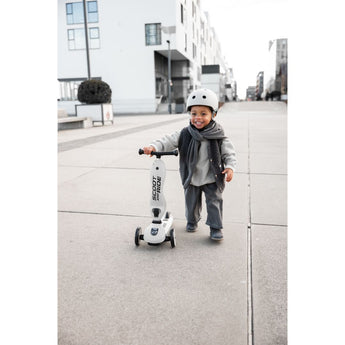Smiling child in helmet with a white Scoot & Ride Highwaykick 1 scooter.