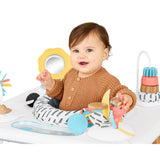 Smiling baby in a Skip Hop Discoverosity 3 Stage Activity Center with colorful toys.