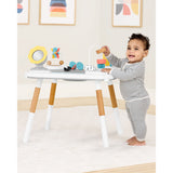Happy baby playing with the white and wood Skip Hop Discoverosity 3 Stage Activity Center.