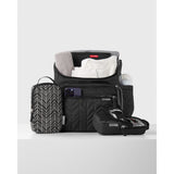 Black quilted Skip Hop Forma Backpack Nappy Bag, open with baby clothes, phone, bottle, and two packing cubes.