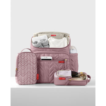 Pink quilted Skip Hop Forma backpack nappy bag, open with baby essentials and two patterned packing cubes.