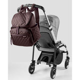 Skip Hop Forma quilted brown backpack nappy bag hanging on a gray stroller handle.