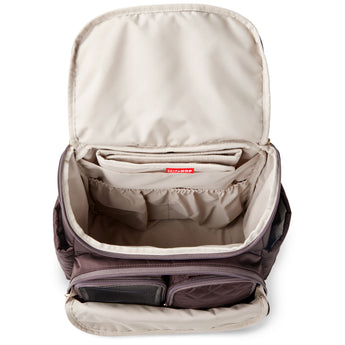 Open Skip Hop Forma quilted backpack in dark brown, showing spacious light interior with multiple pockets.