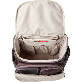 Open Skip Hop Forma quilted backpack in dark purple, showing spacious beige interior with multiple pockets.