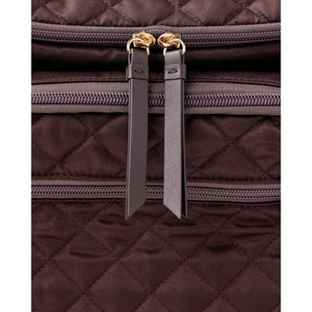 Close-up of a dark brown quilted Skip Hop Forma backpack with gold zippers and leather pulls.