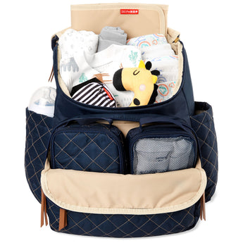Navy quilted Skip Hop Forma backpack diaper bag, open and filled with baby essentials, bottle, and packing cubes.