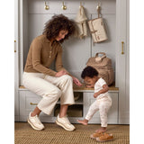 Woman and baby with a tan quilted Skip Hop Forma backpack nappy bag in a mudroom.
