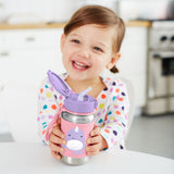 Smiling child holding a pink Skip Hop stainless steel straw water bottle with a purple narwhal design.