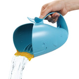 Hand holding a blue whale-shaped Skip Hop Moby Waterfall Rinser pouring water, with a soft yellow rubber lip.
