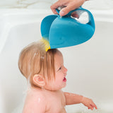 Blue whale-shaped Skip Hop Moby Waterfall Rinser pouring water over a baby's head in a white tub.