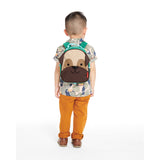 Toddler wearing a Skip Hop Zoolet Pug Mini Backpack with a brown pug face design and green straps.