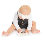 Baby in white top and dark overalls playing with a white Sophie la girafe Magic Mirror SIGHT teething toy.