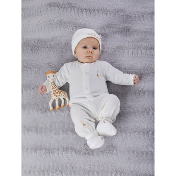 Newborn in white organic cotton Sophie la girafe outfit with matching hat, booties, and giraffe teether on a grey blanket.