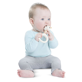 Baby holding a white Sophie la girafe So'Pure natural rubber ring teether.