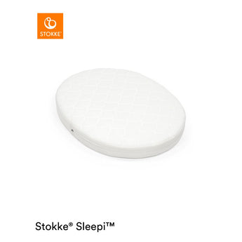 White oval Stokke Sleepi Mini polyurethane foam mattress pad with quilted top.