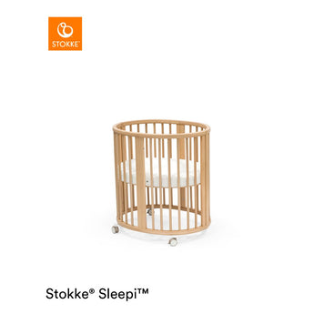 Stokke Sleepi Mini natural wood crib with white polyurethane foam mattress.