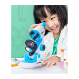 Smiling child looking into a blue and white Discovery Kids microscope.