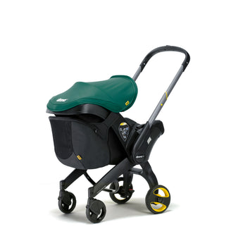 Black Doona Snap-on Storage bag attached to a black Doona stroller with a green canopy.