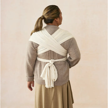 Woman from behind wearing an Ergobaby Aura sustainably sourced knit baby wrap in grey stripes.