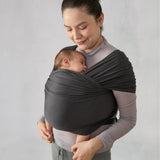 Woman holding sleeping baby in a dark grey Ergobaby Aura knit wrap.