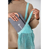Woman holding a folded Ergobaby Away Graphic Grey carrier and placing it into a blue mesh bag.